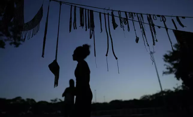 Indigenous crafts girls hang from a clothesline at the Free Earth camp, demanding the government pay more attention to Indigenous issues, in Brasilia, Brazil, Sunday, April 6, 2025. (AP Photo/Eraldo Peres)