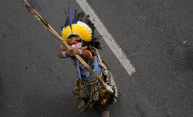 A Pataxo Indigenous aims his traditional bow and arrow during the annual Free Earth camp where Brazil's Indigenous communities discuss rights, territorial protection and their role in COP30 which will take place for the first time in the Amazon, in Brasilia, Brazil, Tuesday, April 8, 2025. (AP Photo/Eraldo Peres)