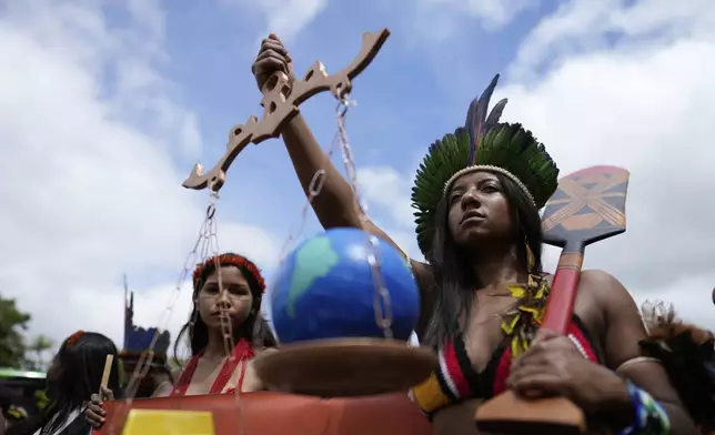 An Indigenous person carries a scale during a march at the annual Free Earth camp where Brazil's Indigenous communities discuss rights, territorial protection and their role in COP30, which will take place for the first time in the Amazon, in Brasilia, Brazil, Tuesday, April 8, 2025. (AP Photo/Eraldo Peres)