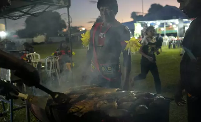 Indigenous people sell roasted fish at the Free Earth camp, demanding the government pay more attention to Indigenous issues, in Brasilia, Brazil, Sunday, April 6, 2025. (AP Photo/Eraldo Peres)