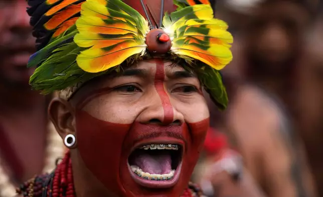A Pataxo Indigenous person sings ritual music during the Free Earth camp held annually to demand more government attention to Indigenous issues in Brasilia, Brazil, Monday, April 7, 2025. (AP Photo/Eraldo Peres)