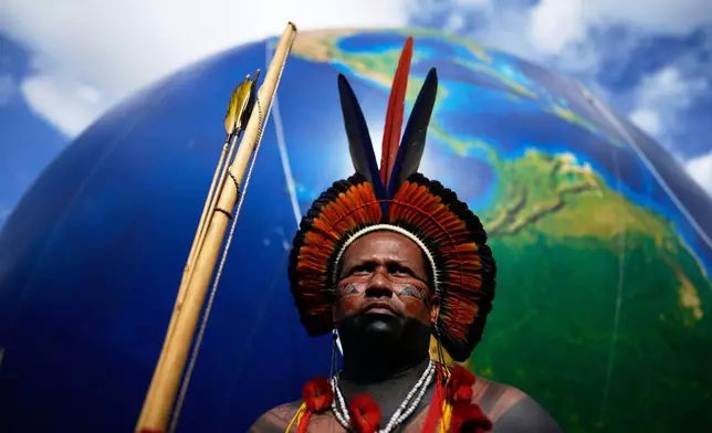An Indigenous man stands next to a large earth balloon during the march coined: "We are the answer" in Brasilia, Brazil, Thursday, April 10, 2025, during the annual Free Earth camp where Brazil's Indigenous people discuss rights, territorial protection and their role in COP30 which will take place for the first time in the Amazon. (AP Photo/Eraldo Peres)