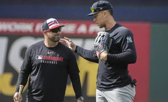 Cleveland Guardians manager Stephen Vogt, left, talks with New York Yankees' Aaron Judge, right, before a baseball game in Cleveland, Monday, April 21, 2025. (AP Photo/Phil Long)