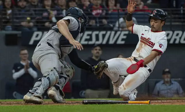 Cleveland Guardians' Steven Kwan, right, slides home as he evades a tag by New York Yankees catcher Austin Wells during the sixth inning of a baseball game in Cleveland, Monday, April 21, 2025. (AP Photo/Phil Long)