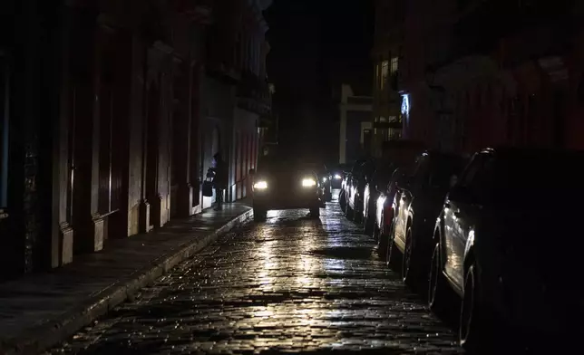 Headlights illuminate cobblestone streets in Old San Juan, Puerto Rico, during an island-wide blackout, Wednesday, April 16, 2025. (AP Photo/Alejandro Granadillo)