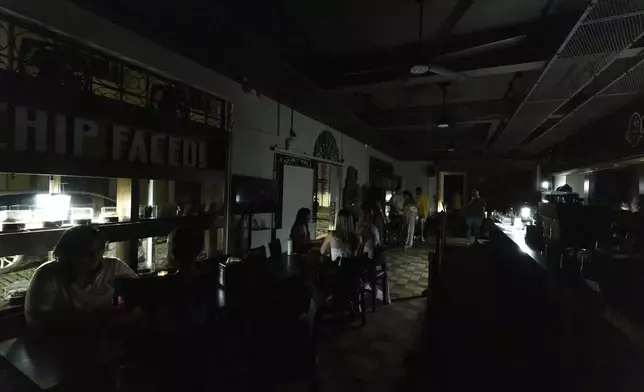 Customers sit inside a restaurant lit by battery-powered lanterns during an island-wide power outage, in Old San Juan, Puerto Rico, Wednesday, April 16, 2025. (AP Photo/Alejandro Granadillo)
