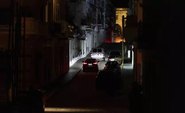 Vehicles navigate a dark street in Old San Juan, Puerto Rico, during an island-wide blackout, Wednesday, April 16, 2025. (AP Photo/Alejandro Granadillo)
