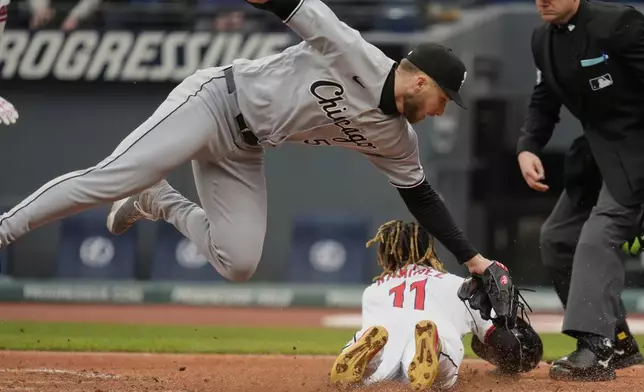 Chicago White Sox starting pitcher Sean Burke falls over Cleveland Guardians' Jose Ramirez, right, as Ramirez slides into home plate to score in the first inning of a baseball game in Cleveland, Wednesday, April 9, 2025. (AP Photo/Sue Ogrocki)