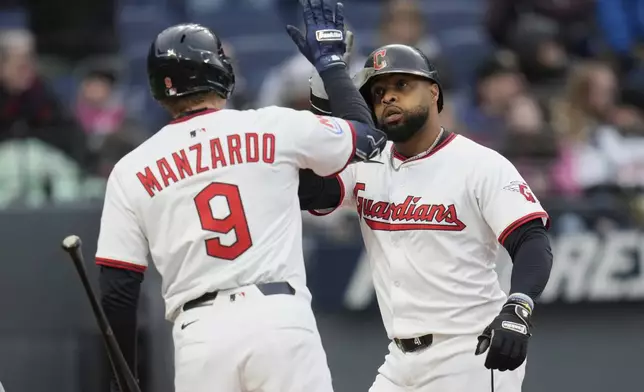 Cleveland Guardians' Carlos Santana, right, gets a high five from teammate Kyle Manzardo (9) after hitting a home run in the third inning of a baseball game against the Chicago White Sox in Cleveland, Wednesday, April 9, 2025. (AP Photo/Sue Ogrocki)