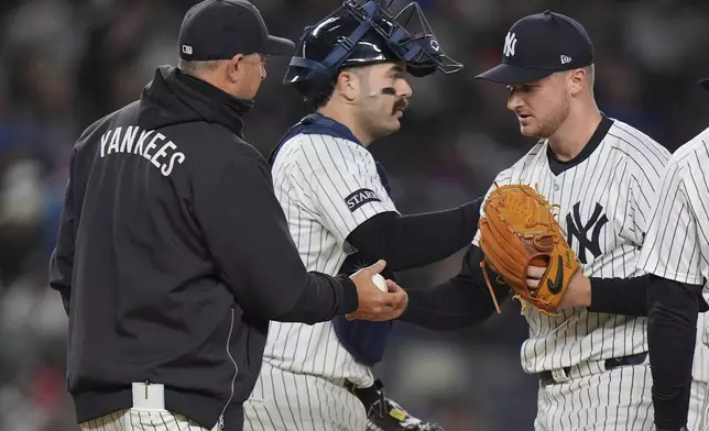 New York Yankees pitcher Clarke Schmidt, right, hands the ball to manager Aaron Boone as he leaves during the sixth inning of a baseball game against the Kansas City Royals Wednesday, April 16, 2025, in New York. (AP Photo/Frank Franklin II)