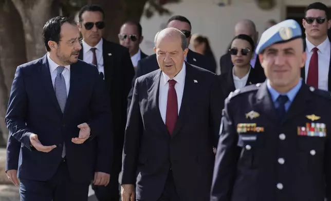 Cyprus' President Nikos Christodoulides, left, and Turkish Cypriot leader Ersin Tatar, centre, walk before their meeting with the U.N. Secretary General's Special Representative in Cyprus Colin Stewart, at a U.N compound inside the U.N controlled buffer zone at abandoned Nicosia airport in divided capital Nicosia, Cyprus, Wednesday, April 2, 2025. (AP Photo/Petros Karadjias)