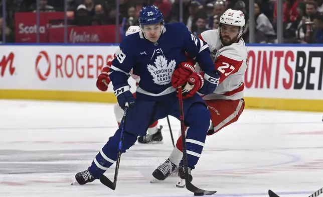 Toronto Maple Leafs' Pontus Holmberg (29) fights for possession of the puck against Detroit Red Wings' Michael Rasmussen (27) during the first period of their NHL hockey game Thursday, April 17, 2025 in Toronto. (Jon Blacker/The Canadian Press via AP)