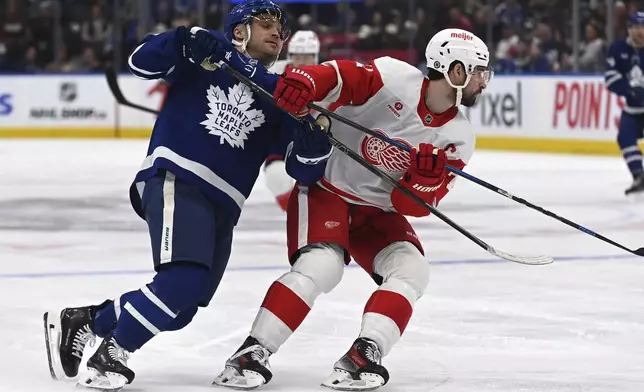 Toronto Maple Leafs' Max Domi, left, battles with Detroit Red Wings' Dylan Larkin, right, during the second period of an NHL hockey game Thursday, April 17, 2025, in Toronto. (Jon Blacker/The Canadian Press via AP)