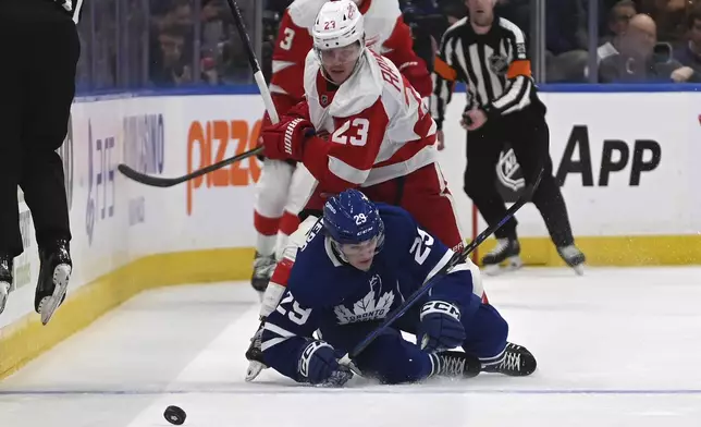 Toronto Maple Leafs' Pontus Holmberg (29) fights for the puck against Detroit Red Wings' Lucas Raymond (23) during the first period of their NHL hockey game Thursday, April 17, 2025 in Toronto. (Jon Blacker/The Canadian Press via AP)