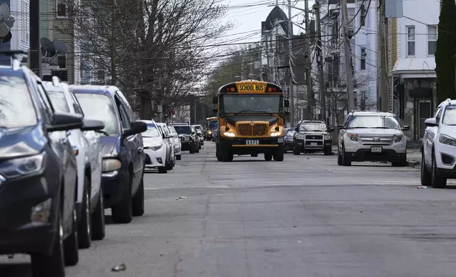 A school bus rolls through a neighborhood near where ICE officers took a man into custody after breaking the window of the family car, Wednesday, April 16, 2025, in New Bedford, Mass. (AP Photo/Charles Krupa)
