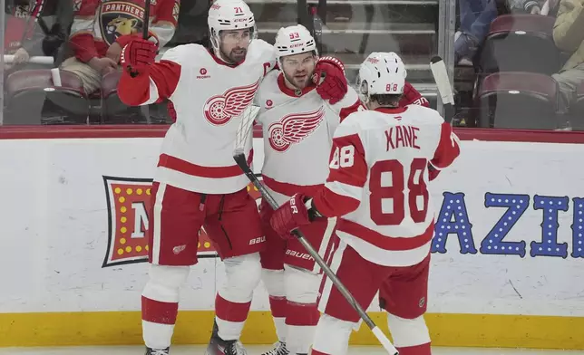 Detroit Red Wings right wing Alex DeBrincat (93) is congratulated by his teammates after scoring a goal during the first period of an NHL hockey game against the Florida Panthers, Thursday, April 10, 2025, in Sunrise, Fla. (AP Photo/Marta Lavandier)
