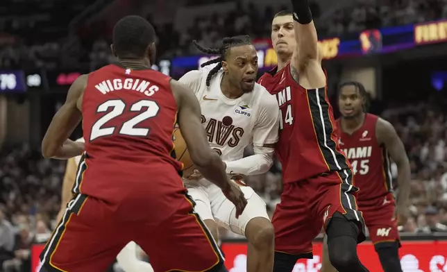 Cleveland Cavaliers guard Darius Garland, center, drives between Miami Heat forward Andrew Wiggins (22) and guard Tyler Herro (14) in the second half in Game 1 of an NBA first-round playoff series, Sunday, April 20, 2025, in Cleveland. (AP Photo/Sue Ogrocki)