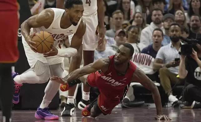 Miami Heat forward Andrew Wiggins, right, reaches for the ball as Cleveland Cavaliers guard Donovan Mitchell (45) heads up the court in the second half in Game 1 of an NBA first-round playoff series, Sunday, April 20, 2025, in Cleveland. (AP Photo/Sue Ogrocki)