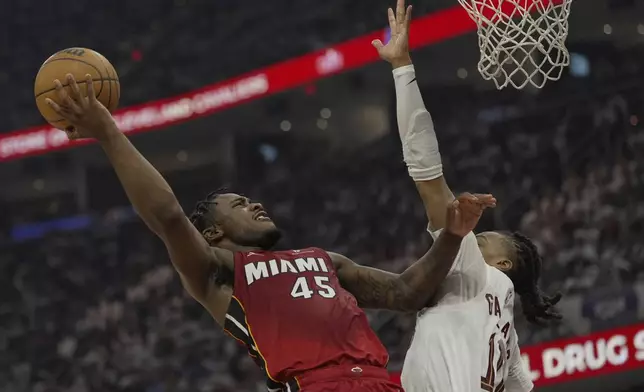 Miami Heat guard Davion Mitchell (45) shpts as Cleveland Cavaliers guard Darius Garland, right, defends in the first half in Game 1 of an NBA first-round playoff series, Sunday, April 20, 2025, in Cleveland. (AP Photo/Sue Ogrocki)