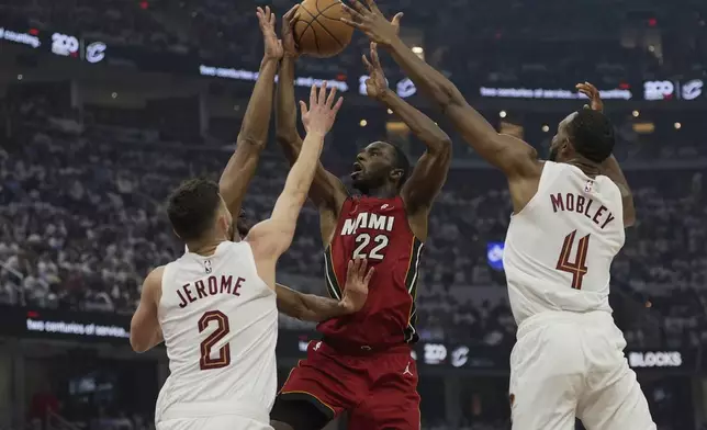 Miami Heat forward Andrew Wiggins (22) shoots between Cleveland Cavaliers forward De'Andre Hunter, behind guard Ty Jerome (2) and Evan Mobley (4) in the first half in Game 1 of an NBA first-round playoff series, Sunday, April 20, 2025, in Cleveland. (AP Photo/Sue Ogrocki)