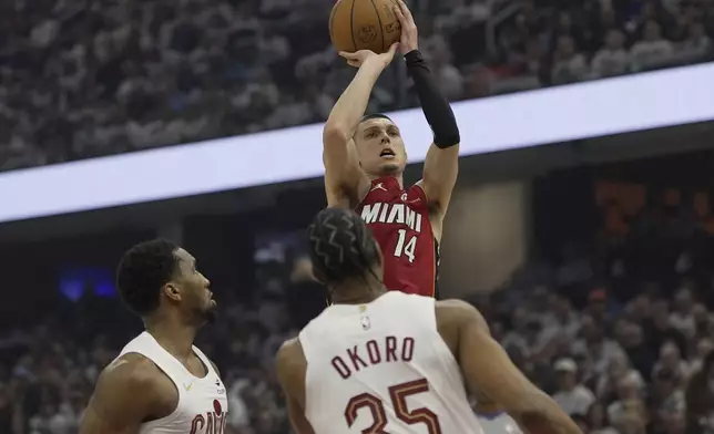 Miami Heat guard Tyler Herro (14) shoots in front of Cleveland Cavaliers guard Donovan Mitchell, left, and forward Isaac Okoro (35) in the first half in Game 1 of an NBA first-round playoff series, Sunday, April 20, 2025, in Cleveland. (AP Photo/Sue Ogrocki)