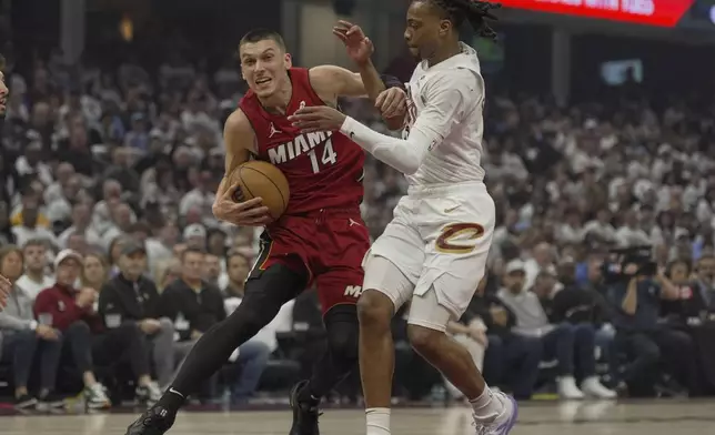 Miami Heat guard Tyler Herro (14) drives against Cleveland Cavaliers guard Darius Garland, right, in the first half in Game 1 of an NBA first-round playoff series, Sunday, April 20, 2025, in Cleveland. (AP Photo/Sue Ogrocki)