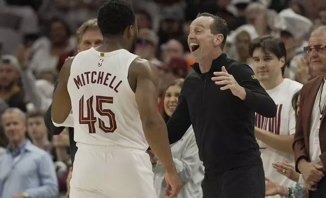 Cleveland Cavaliers head coach Kenny Atkinson, right, greets guard Donovan Mitchell (45) as he returns to the bench late in the second half in Game 1 of an NBA first-round playoff series against the Miami Heat, Sunday, April 20, 2025, in Cleveland. (AP Photo/Sue Ogrocki)