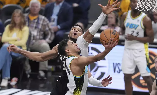 Indiana Pacers' Tyrese Haliburton, front, heads to the basket as Milwaukee Bucks' Giannis Antetokounmpo defends during the second half of a first-round NBA basketball playoff game, Saturday, April 19, 2025, in Indianapolis. (AP Photo/Michael Conroy)