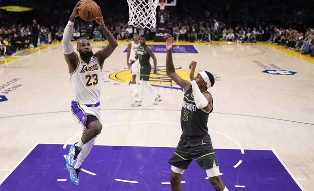 Los Angeles Lakers forward LeBron James, left, goes up for a dunk as Minnesota Timberwolves forward Jaden McDaniels, right, defends during the second half in Game 1 of an NBA first-round playoff series Saturday, April 19, 2025, in Los Angeles. (AP Photo/Mark J. Terrill)