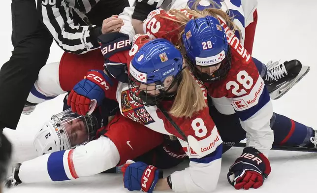 Tereza Pistekova of Czech Republic, center, and Noemi Neubauerova of Czech Republic, right, check United States' Cayla Barnes during the semi final match between Czech Republic and United States at the Women's Ice Hockey Championships in Ceske Budejovice, Czech Republic, Saturday, April 19, 2025. (AP Photo/Petr David Josek)