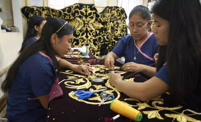 Weavers apply gold-colored pieces to a tunic for a statue of the Virgin Mary at the Maria Auxiliadora embroidery workshop in San Miguel Escobar, Guatemala, Wednesday, April 2, 2025. (AP Photo/Moises Castillo)