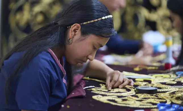 A weaver applies gold-colored pieces to the tunic to be worn by a statue of the Virgin Mary, at the Maria Auxiliadora embroidery workshop in San Miguel Escobar, Guatemala, Wednesday, April 2, 2025. (AP Photo/Moises Castillo)