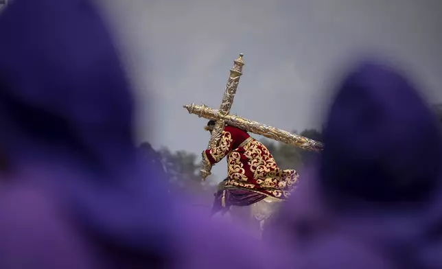 Faithful carry a wooden platform with a statue of Jesus of Nazareth, wearing a tunic created by weavers at the Maria Auxiliadora embroidery workshop, during a Lenten season procession in Antigua, Guatemala, Sunday, April 6, 2025. (AP Photo/Santiago Billy)