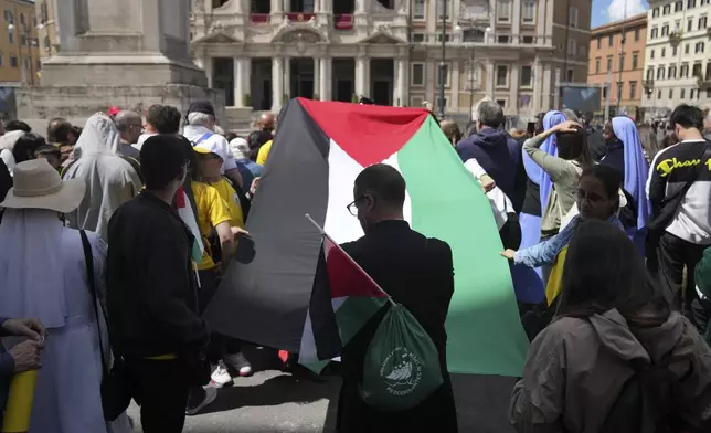 People hold a Palestinian flag outside of the St. Mary Major Basilica where Pope Francis was burried in Rome Saturday, April 26, 2025. (AP Photo/Francisco Seco)