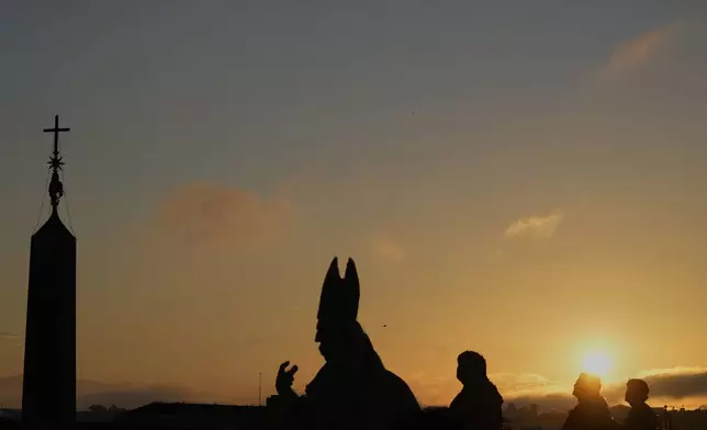 Statues on the Charlemagne Wing are silhouetted as the sun rises ahead of the funeral of Pope Francis in St. Peter's Square at the Vatican, Saturday, April 26, 2025. (AP Photo/Gregorio Borgia)