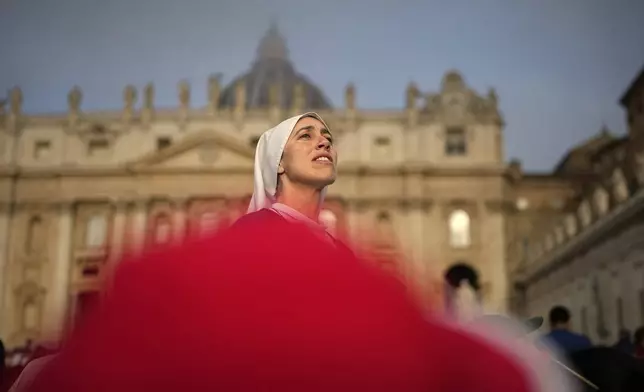 A nun looks above the crowds as people gather for the funeral of Pope Francis in St. Peter's Square at the Vatican, Saturday, April 26, 2025. (AP Photo/Andreea Alexandru)