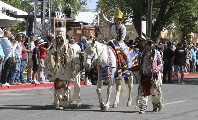 A participant in the Gathering of Nations horse parade waves to the crowd at the state fairgrounds in Albuquerque, New Mexico, on Friday, May 25, 2025 (AP Photo/Susan Montoya Bryan)