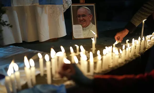 Faithful light candles under a highway bridge during Mass to honor the late Pope Francis in the Carlos Mugica neighborhood of Buenos Aires, Argentina, Monday, April 21, 2025. (AP Photo/Rodrigo Abd)