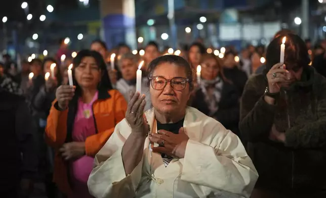 Faithful hold candles during a Mass honoring the late Pope Francis under a highway bridge in the Carlos Mugica neighborhood of Buenos Aires, Argentina, Monday, April 21, 2025. (AP Photo/Rodrigo Abd)