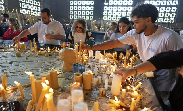 Worshippers light candles at the Sanctuary of Our Lady of Aparecida, following the Vatican's announcement the death of Pope Francis, in Aparecida, Brazil Monday, April 21, 2025. (AP Photo/Andre Penner)