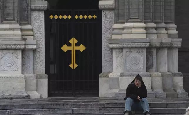 A woman sits on the steps of the Wangfujing Catholic Church also known as East Church in Beijing, Monday, April 21, 2025. (AP Photo/Ng Han Guan)