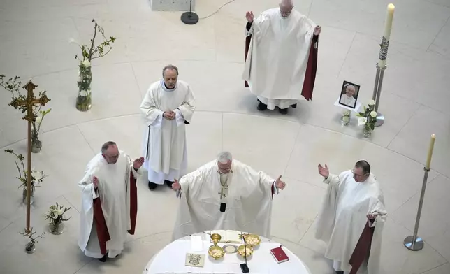 Priests pray next to a photo of the late Pope Francis during a prayer service at the Saint Hedwig's Cathedral in Berlin, Germany, Monday, April 21, 2025. (AP Photo/Ebrahim Noroozi)