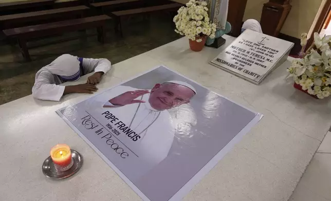 A Catholic nun of the Missionaries of Charity, the order founded by Saint Teresa, prays as a portrait of Pope Francis is placed over the tomb following his death, in Kolkata, India, Tuesday, April 22, 2025. (AP Photo/Bikas Das)