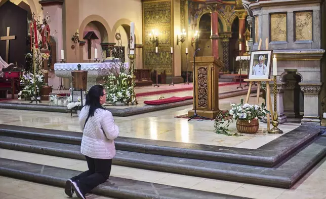 A woman prays in front of a photo of the late Pope Francis after the news of his death at age 88, at the Basilica of St. John the Baptist near the Vatican embassy in Berlin, Germany, Monday, April 21, 2025. (AP Photo/Markus Schreiber)