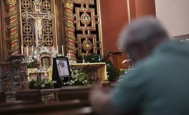 City commissioner Kirk Menendez, who as a Catholic government official had the opportunity to meet Pope Francis at the Vatican in August 2024, bows his head in prayer as he pays his respects near a picture of the Pope displayed inside Church of the Little Flower, Monday, April 21, 2025, in Coral Gables, Fla. (AP Photo/Rebecca Blackwell)