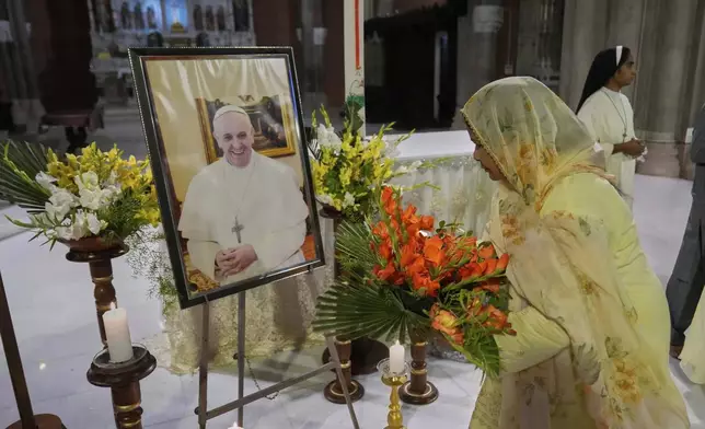 A Christian places a bouquet in front of the portrait of Pope Francis during a prayer ceremony at the Cathedral Church of the Resurrection, in Lahore, Pakistan Monday, April 21, 2025, following the announcement by the Vatican of the death of Pope Francis. (AP Photo/K.M. Chaudary)