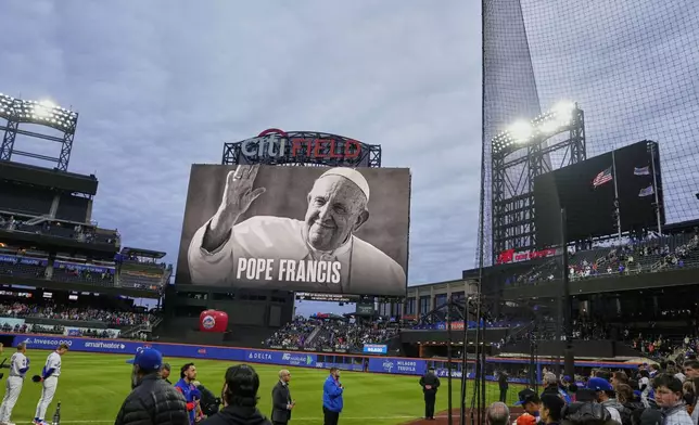 Fans and players stand during a moment of silence as a portrait of Pope Francis is displayed at Citi Field before a baseball game between the New York Mets and the Philadelphia Phillies Monday, April 21, 2025, in New York. (AP Photo/Frank Franklin II)