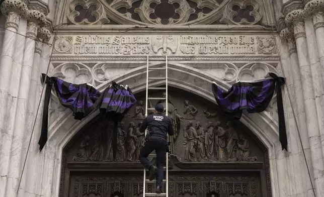 NYPD officer installs bunting ribbons outside St. Patrick's Cathedral, Monday, April 21, 2025, in New York. (AP Photo/Yuki Iwamura)
