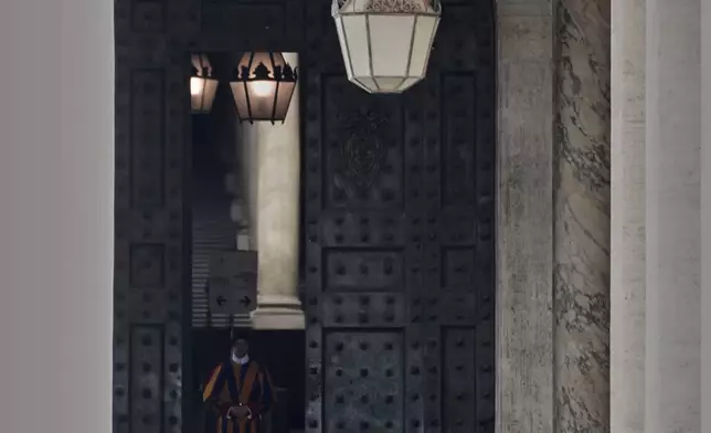 A Pontifical Swiss Guards stand by the Vatican Bronze door half closed after Pope Francis died, in St. Peter's Square at the Vatican Sunday, April 20, 2025.(AP Photo/Andrew Medichini)