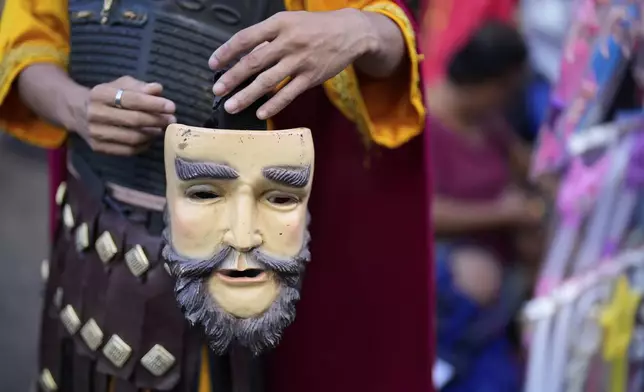 A performer dressed as a Roman soldier prepares his mask during a reenactment of the passion and sufferings of Jesus Christ on Maundy Thursday in Paete town, Laguna province, Philippines, April 17, 2025. (AP Photo/Aaron Favila)